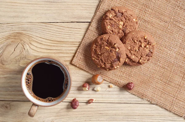 Kahve ve çikolata parçalı kurabiye fındık üzerinde ahşap masa, üstten görünüm ile fincan