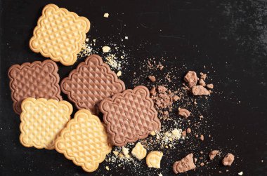 Vanilya ve çikolata kare kurabiye bütün ve kırık eski siyah metal arka planda üstten görünüm