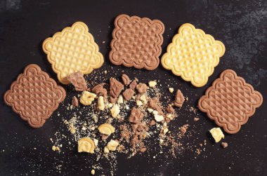 Çikolata ve vanilya kare çerezleri tüm ve kırık eski siyah metal arka planda üstten görünüm