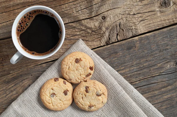 在一张旧的木桌上 一杯咖啡和饼干配上亚麻布上的巧克力 — 图库照片