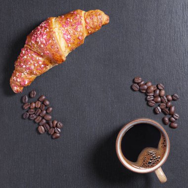 Fincan kahve ve kruvasan ile siyah taş zemin üzerine ahududu reçeli, kopya alanı ile üstten görünüm