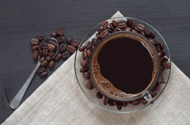 Cam fincan sıcak kahve ve siyah ahşap arka plan, üstten görünüm fasulye