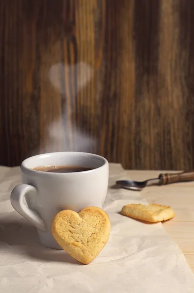 Cookies in the shape of a heart  and cup of coffee on wooden table