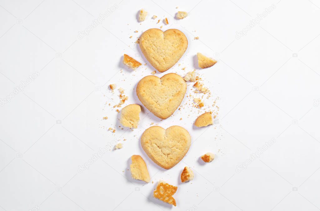 Shortbread cookies in shape of heart whole end broken on white background, top view with space for text