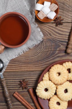 Bir fincan çay, kurabiye kurabiye plaka, baharatlar ve ahşap masa, üstten görünüm üzerinde şeker. Ortasında metin için bir yer var.