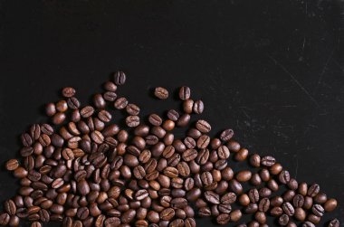 Kahve çekirdekleri eski siyah metal arka plan üzerinde dağınık. Senin metin için yer