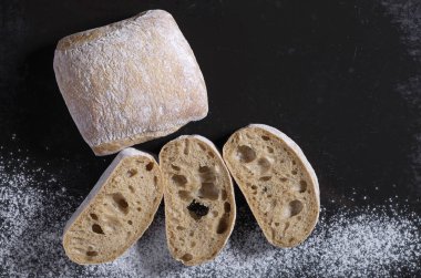 Ciabatta somun ekmek ve eski siyah metal arka plan üzerinde dilimlenmiş, kopya alanı görünümüyle üst