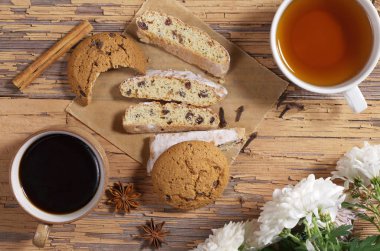 Fincan kahve ve çay, sırlı gingerbread dilimleri, yulaf ezmeli kurabiye, çiçek ve baharat eski ahşap tablo, üstten görünüm