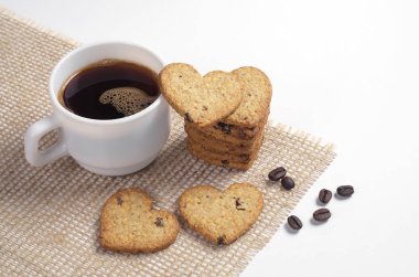 Fincan kahve ve beyaz arka plan üzerinde kalp şeklinde kurabiye