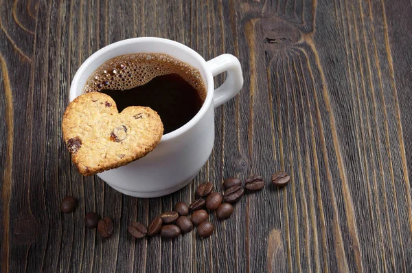 一杯のコーヒーと暗い木製のテーブルの上のハートの形をしたクッキーをクローズ アップ — ストック写真