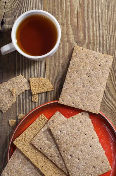 一杯茶和清脆的面包在红盘子上的木桌上 顶视图 饮食食品 — 图库照片