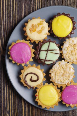 Buzlanma yakın koyu ahşap arka plan üzerinde gri plaka ile çeşitli cupcakes kontör, görünümü