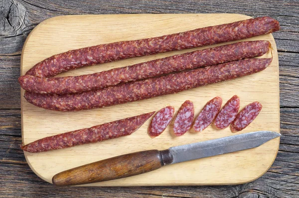 Slim Smoked Sausage Old Knife Cutting Board Located Wooden Background — Stock Photo, Image