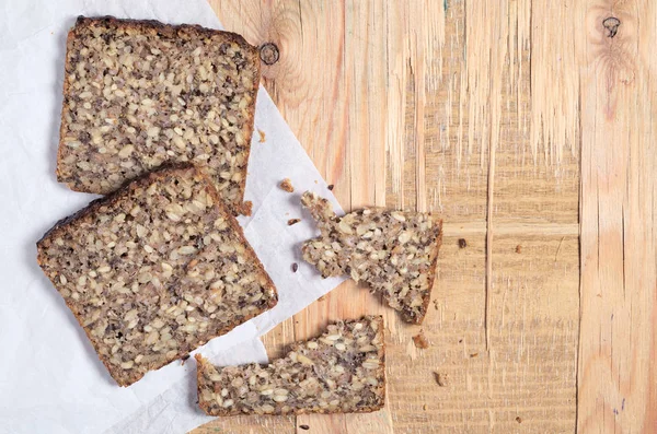 Sneetjes Brood Met Verschillende Zaden Papier Gelegen Oude Houten Achtergrond — Stockfoto