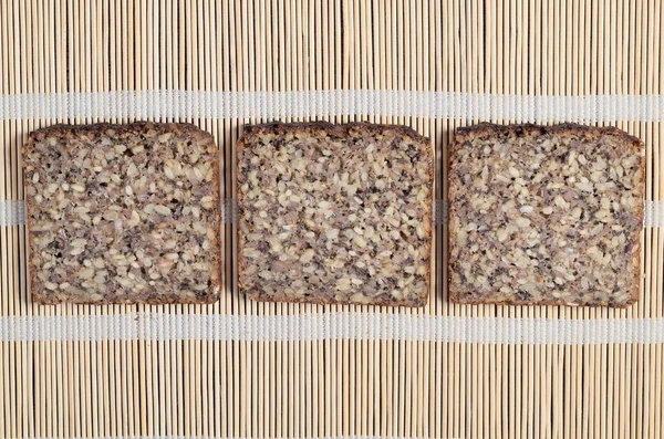 Три Ломтика Хлеба Различными Семенами Фоне Салфетки Бамбука Вид Сверху — стоковое фото