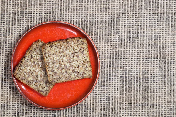 Sneetjes Brood Met Verschillende Zaden Een Rode Plaat Achtergrond Van — Stockfoto