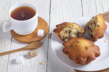 Bir tabak ve bardak çay beyaz tahta masada üzümlü kek