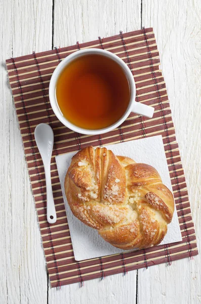 甘い籐パンと竹ナプキンに紅茶のカップが古い白い木製のテーブル 平面図に配置します — ストック写真