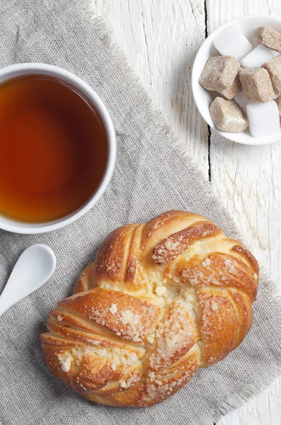 新鲜的面包 一杯茶和织物上的糖块位于白色的木桌上 顶视图 — 图库照片