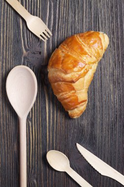 Kruvasan ve karanlık tablo, üstten görünüm çeşitli tahta çatal bıçak takımı