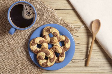 Tatlı kurabiye ve kahve ahşap bir masa üzerinde bulunan çuval bezi üzerinde mavi yemeklerinde görünümü top