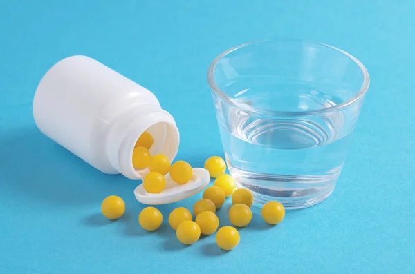 Gelbe Vitaminpillen und Wasser — Stockfoto