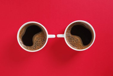 Kırmızı arka planda iki fincan kahvenin tam üstünde.