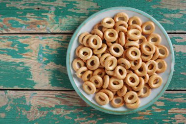 Eski yeşil ahşap zemin üzerindeki bir tabakta kurutma veya mini simit, kopyalama alanı olan üst görünüm