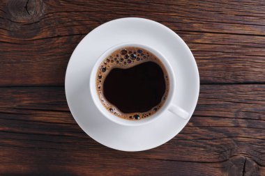 Ahşap arka planda bir fincan kahve, yakın plan, üst manzara.