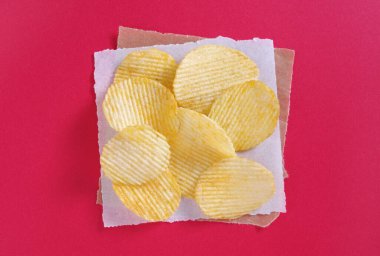 Kırmızı arka planda lezzetli patates cipsi, üst manzara.