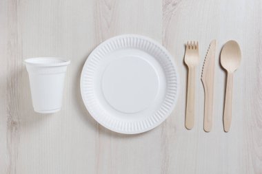 Masada tek kullanımlık tabaklar, üst manzara. Cam, tabak, kaşık, çatal, bıçak.