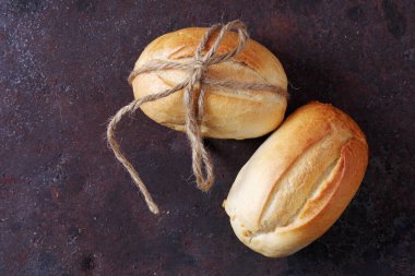 Paslı metal arka planda sicimle bağlanmış iki somun küçük buğday ekmeği.