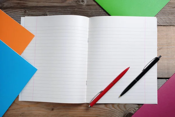 木制背景的彩色学校笔记本和两支圆珠笔 顶视图 — 图库照片