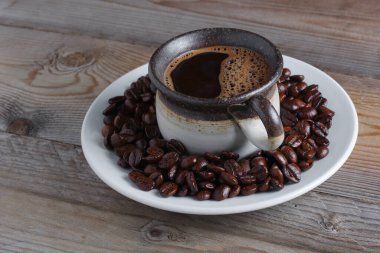 Bir fincan kahve ve kavrulmuş fasulye yakın plan masa üzerinde.