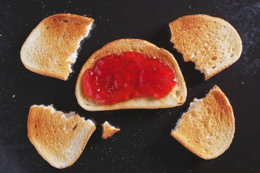 Çilek reçelli bir dilim tost ve eski siyah metal tepside birkaç parça.