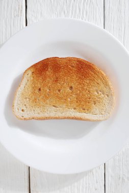 Beyaz ahşap zemin üzerinde bir tabak kızarmış ekmek, üst manzara.
