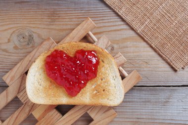 Kalp şeklinde reçel tost ekmeği ahşap masa, üst manzara