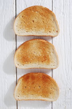 Beyaz ahşap zemin üzerinde kavrulmuş ekmek dilimleri, üst manzara
