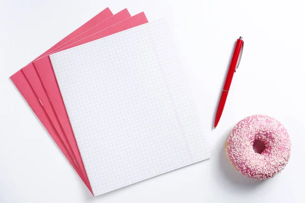 Schulhefte Und Rosa Donut Auf Weißem Hintergrund Draufsicht — Stockfoto