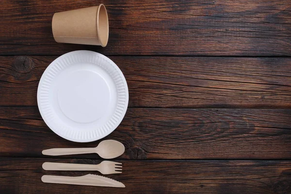 Directly above view of disposable tableware and cutlery on wooden background