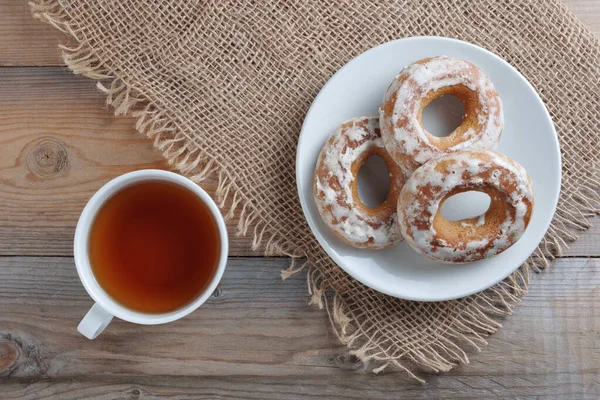 木制背景的茶杯和釉面百吉饼 顶部视图 — 图库照片