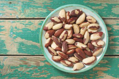 Brezilya eski yeşil ahşap zemin üzerinde tabak fındık, kopyalama alanı ile üst görünüm