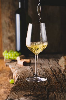 Wine. Glass of white wine in wine cellar. Old white wine on wood. Wine pouring froma bottle clipart
