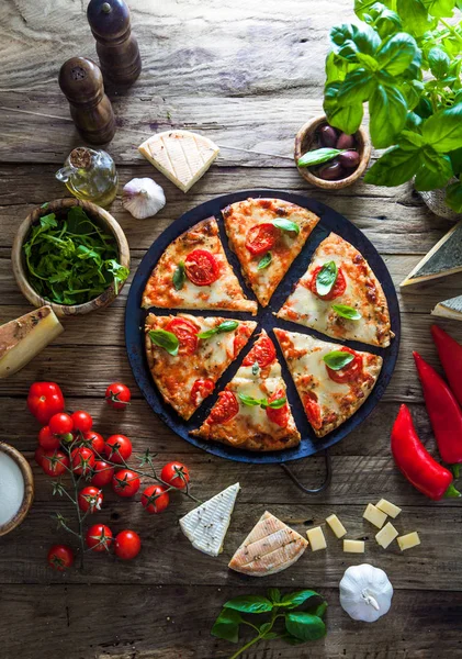 Pizza on wood with ingredients — Stock Photo, Image
