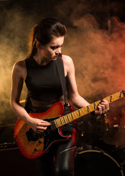 Young female with guitar on stage