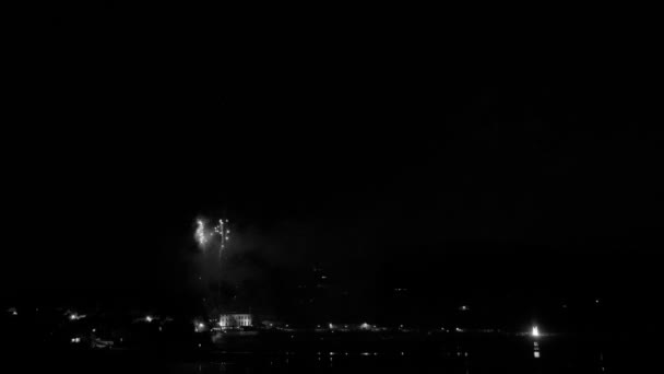 黒と白の海岸沿いの町の上のビーチからの花火のタイムラプス フッテージの中央に火花をプログレッシブズーム — ストック動画