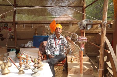 FARIDABAD, HARYANA / INDIA - FEBRUARY 16 2018: Hookah Seller at The Surajkund Crafts Mela - The largest Crafts Fair in the world with over 1 million visitors  clipart