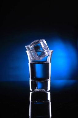 Mavi zemin üzerine bir buz küpü ile içki kadehi
