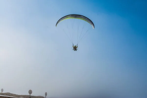 Parachutist flies against the blue sky. Motorized parachute