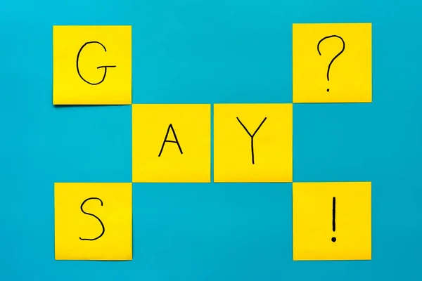 Handgeschriebene schwarze Aufschrift gay and say auf gelben quadratischen Aufklebern auf blauem Hintergrund — Stockfoto